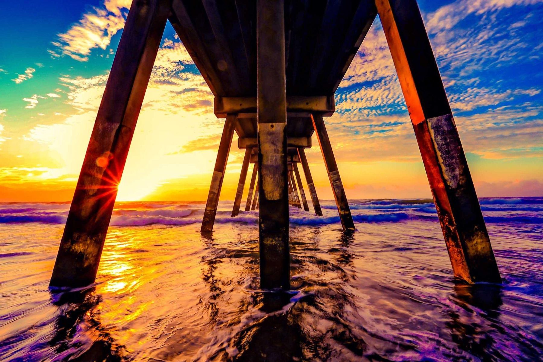 Ein Steg im Meer bei Sonnenuntergang, umgeben von seinem eigenen Licht